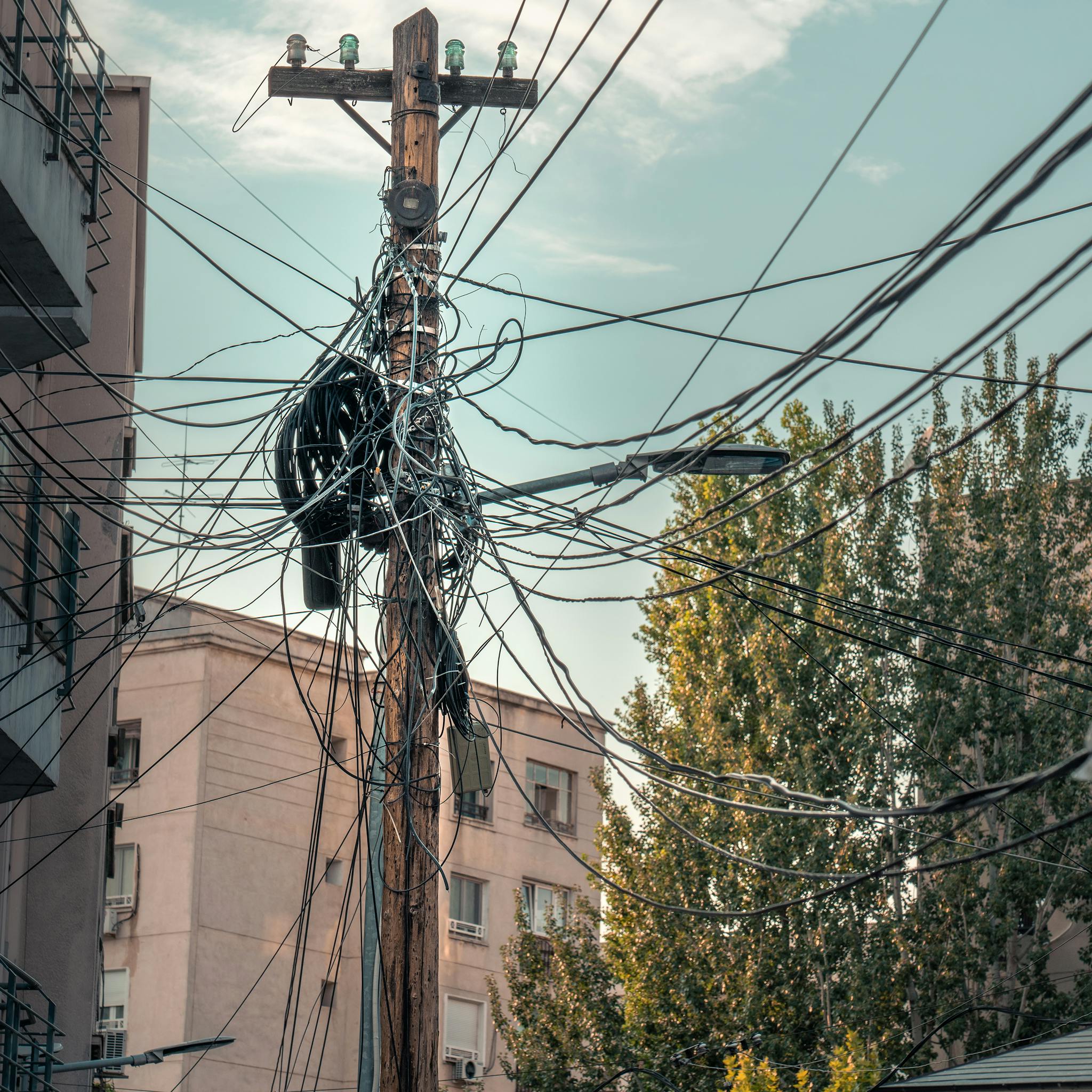 A messy web of power lines and cables on a street in București, Romania, showcasing urban infrastructure.